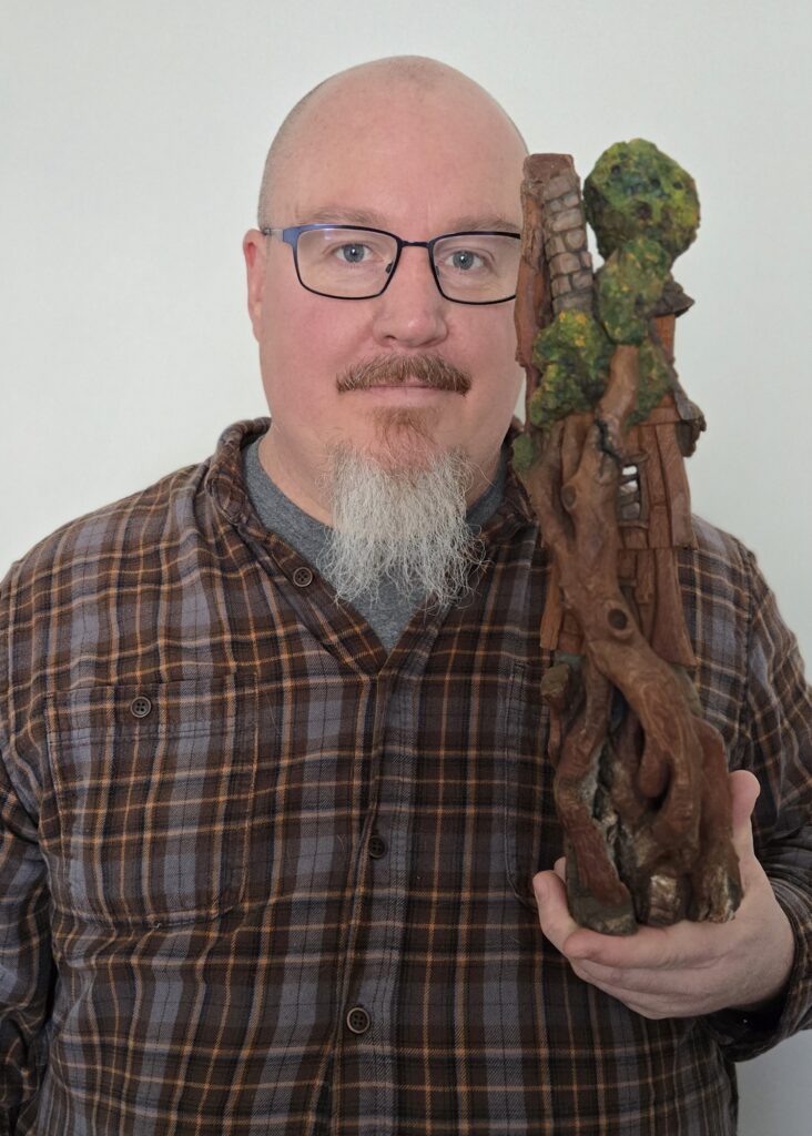 Joshua Walters holds a carved bark cottage