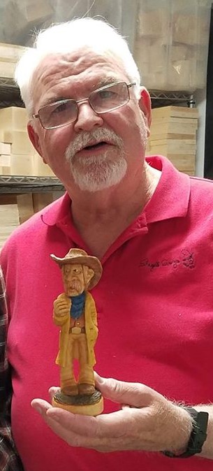 Caricature carving instructor holds a carving of a cowboy